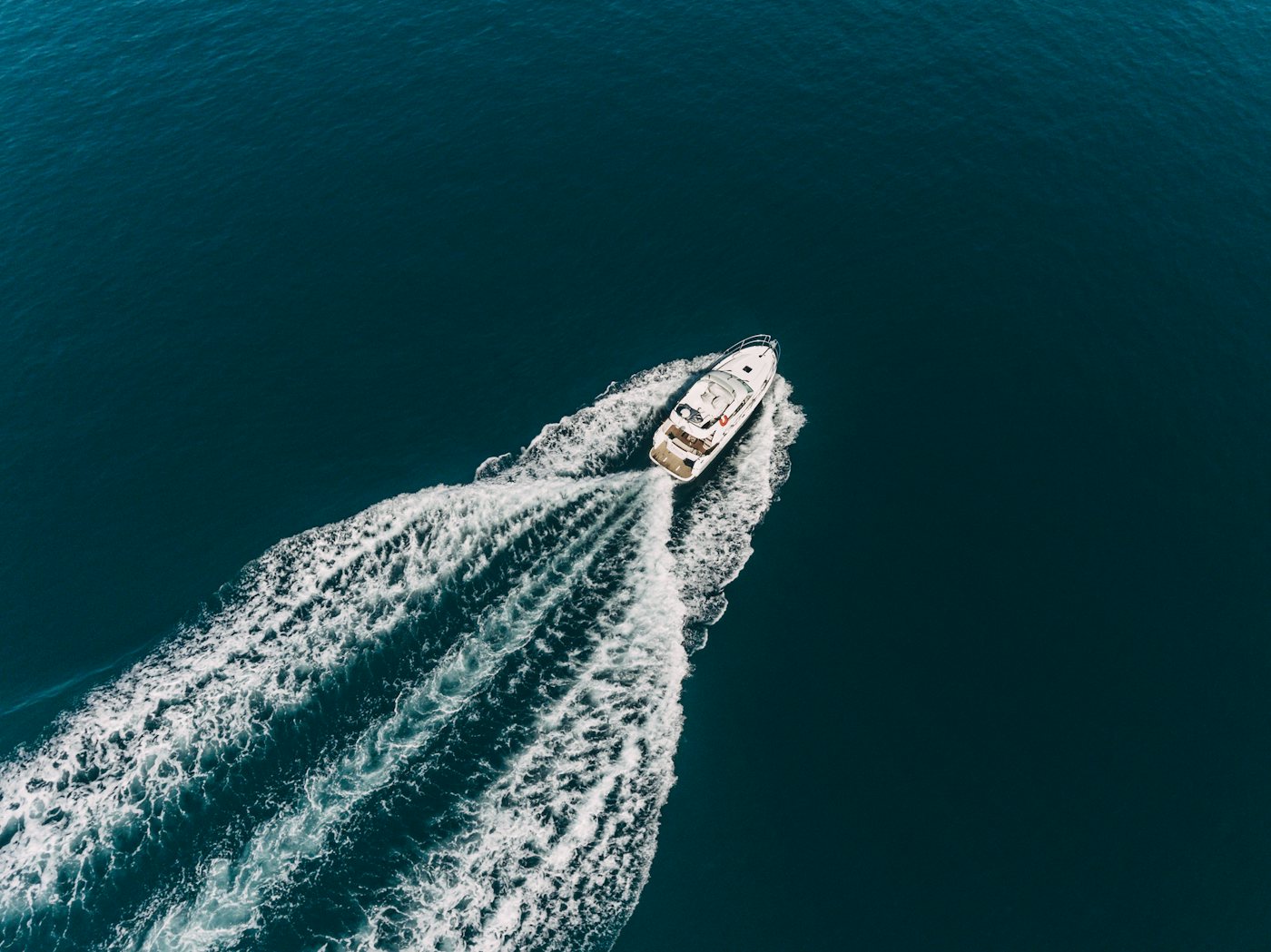 A motor yacht cutting a white wake through deep blue water