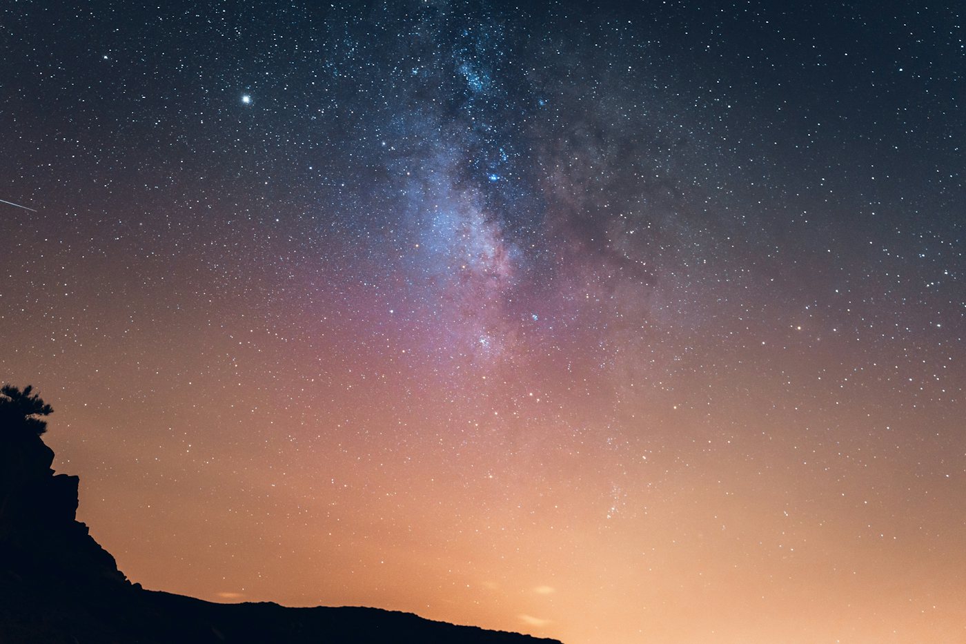 The silhouette of a volcano under a deep blue night sky