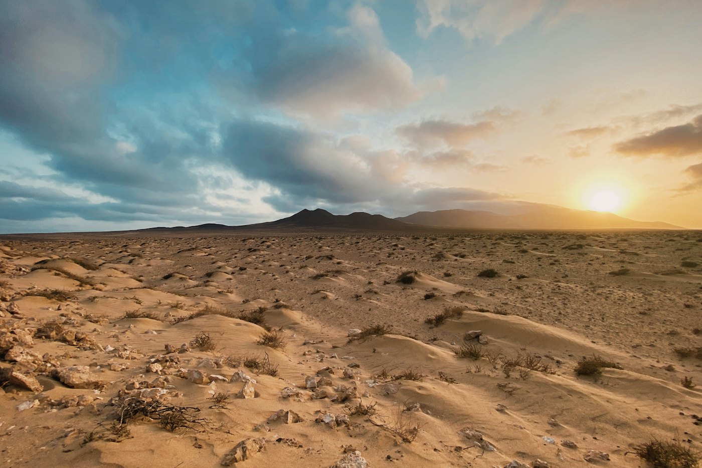 The sun setting over sand dunes and low volcanic hills in Fuerteventura