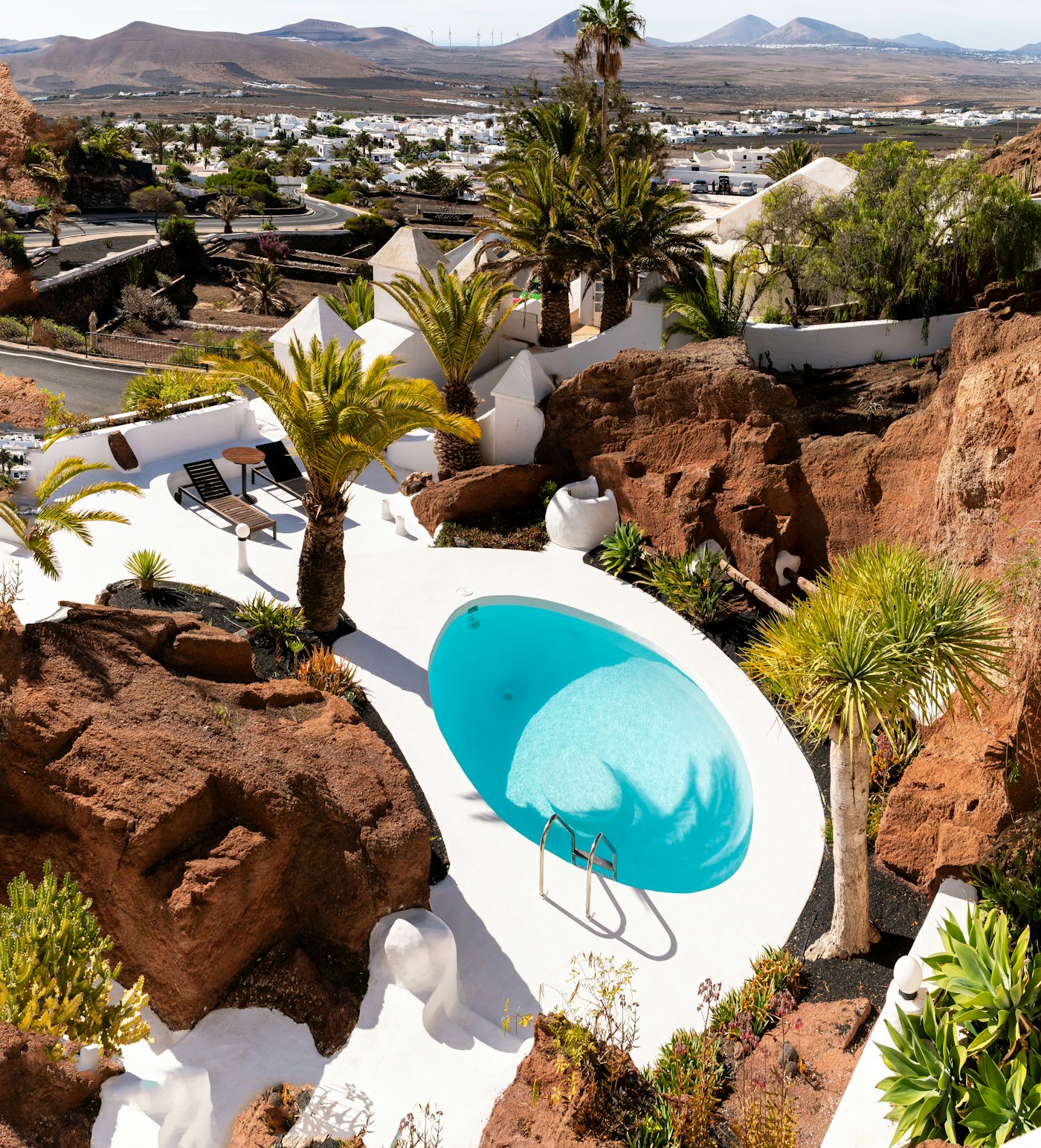 La piscina de una villa privada entre roca volcánica negra y palmeras