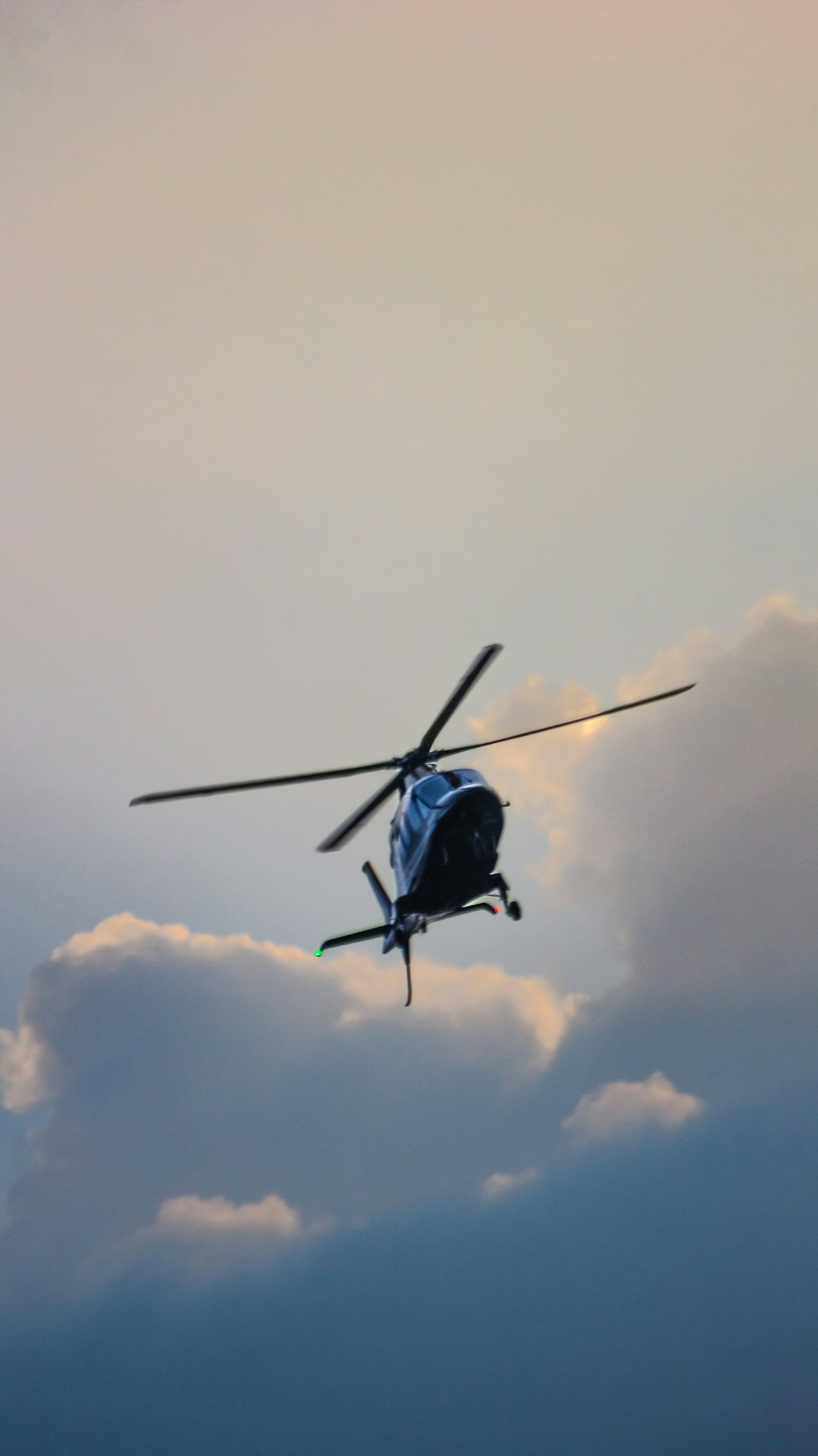 A dark private helicopter against golden evening clouds