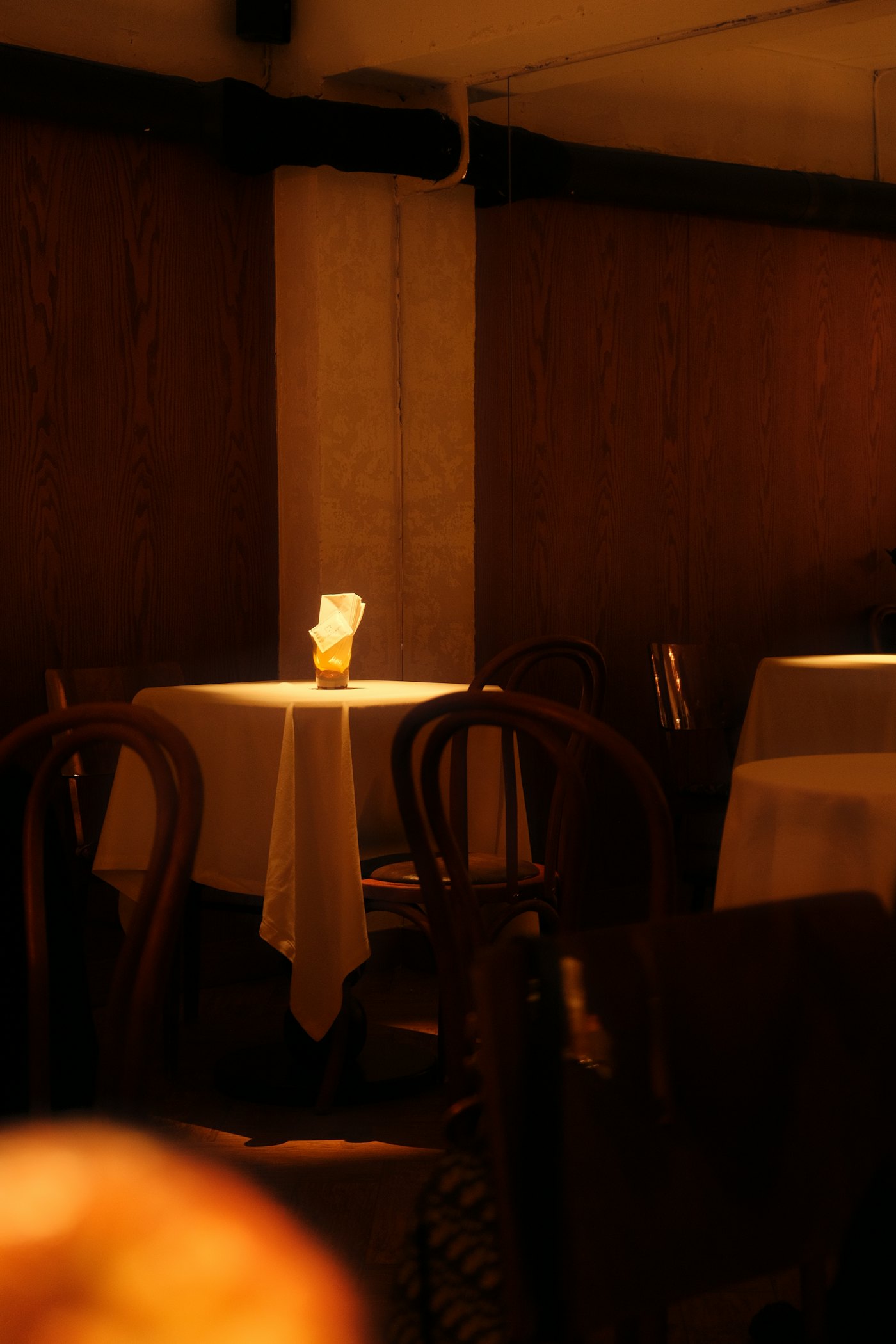 A single candle on a dimly lit table set for dinner