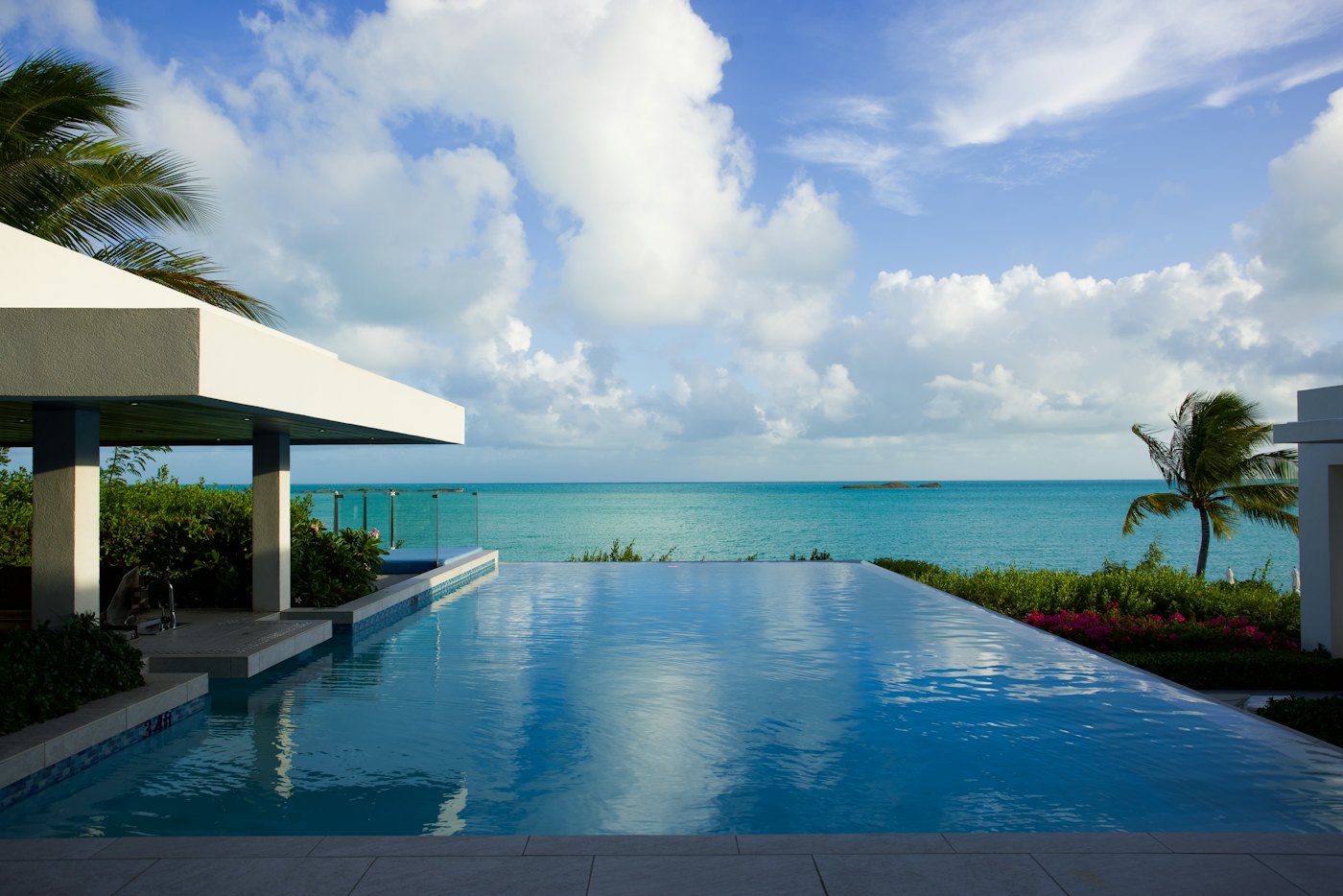 An infinity pool above a turquoise sea under a clear sky